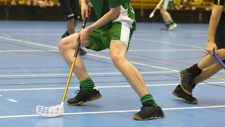 floorball kamp kun ben og blaat gulv - en spiller med stav og bold