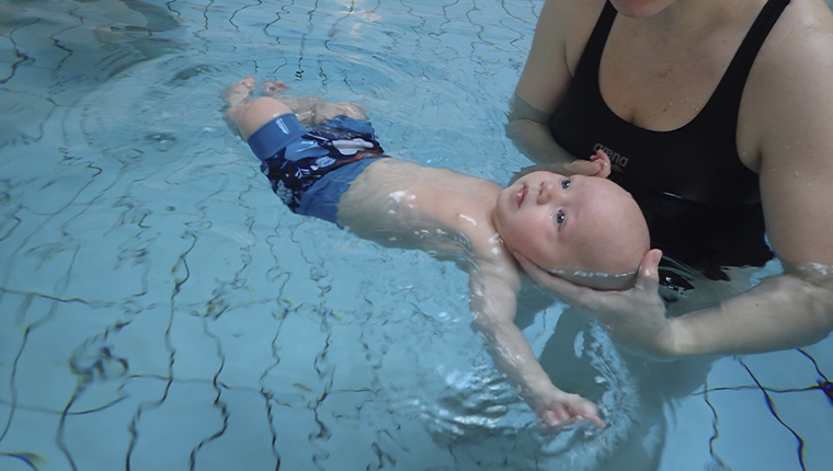 AMO lille baby flyder i vand stoettet ved hovede
