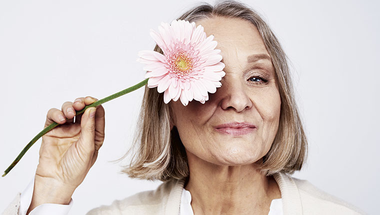 kvinde 50+ holder blomst ved ansigtet
