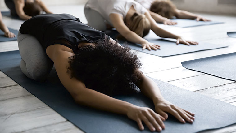 Mennesker på yogamåtter med ansigterne nedad