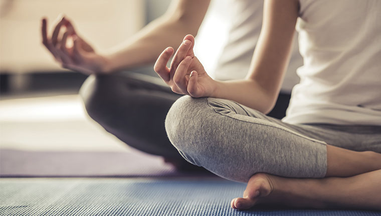 Personer sidder i skrædderstilling på yogamåtter