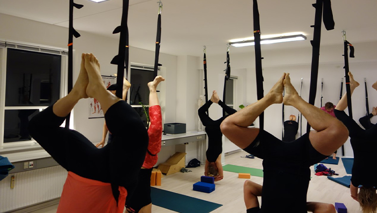 Ananda Yoga - hele salen fyldt med personer som dyrker  yoga med hovedet nedad